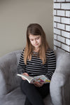 a girl sitting in a chair reads a book