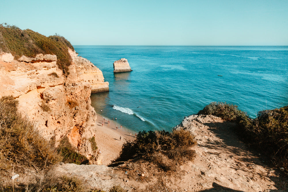 a golden beach below a cliff