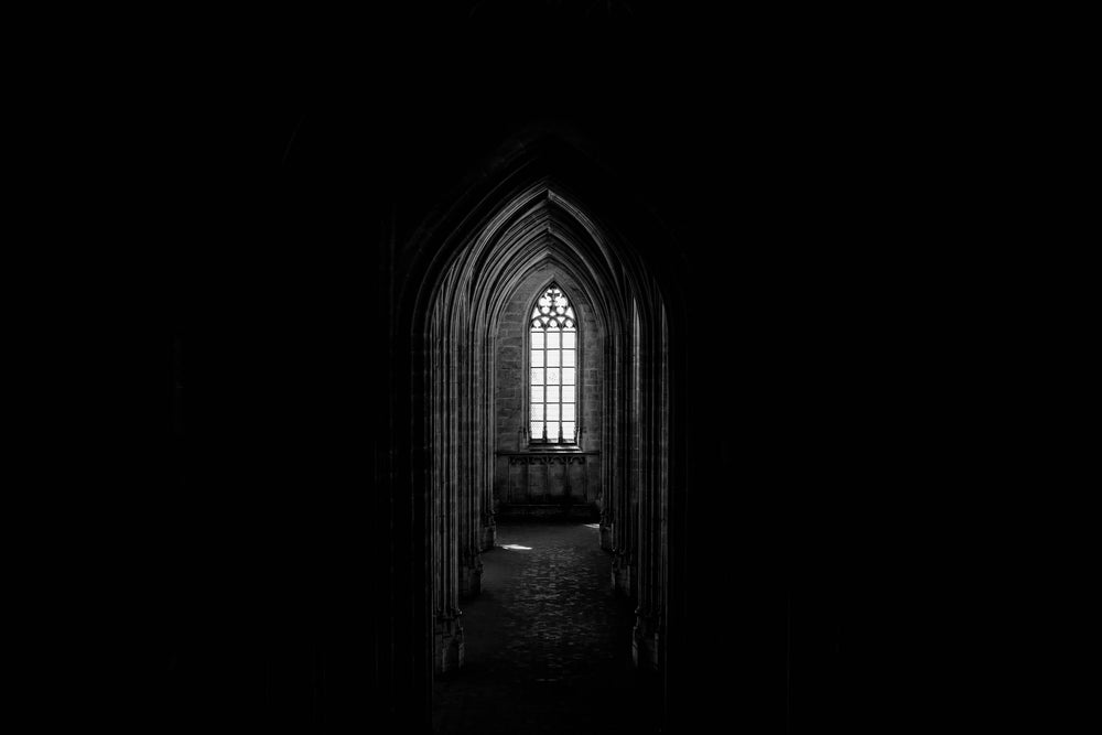 a gothic church window illuminates a corridor of archways