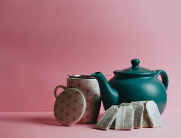 a green teapot and teabags leaning on it