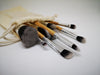 a group of paint brushes spill out of a cream linen bag