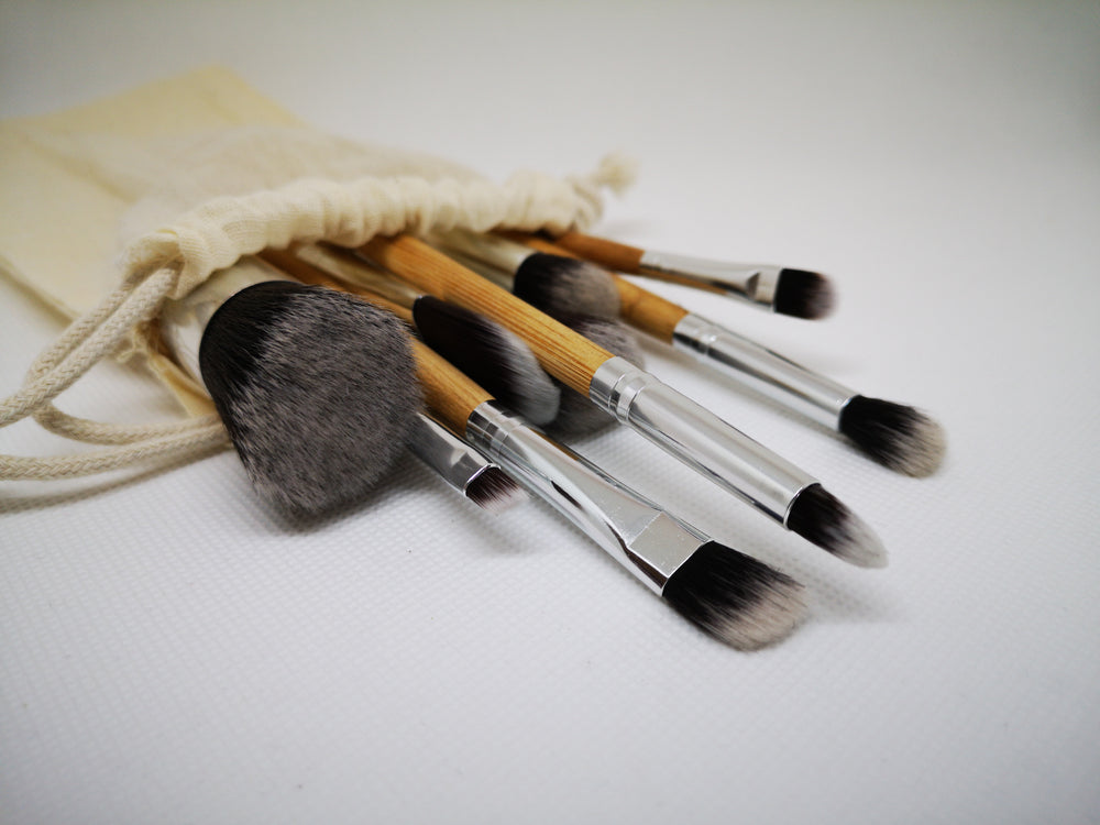 a group of paint brushes spill out of a cream linen bag