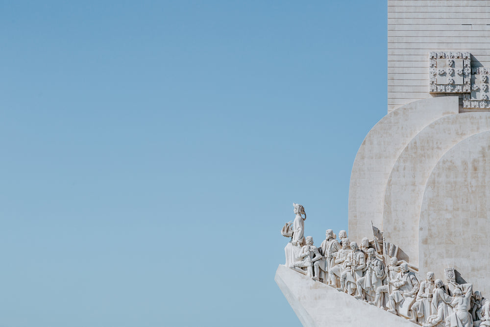 a group of statues on the edge of white stone building