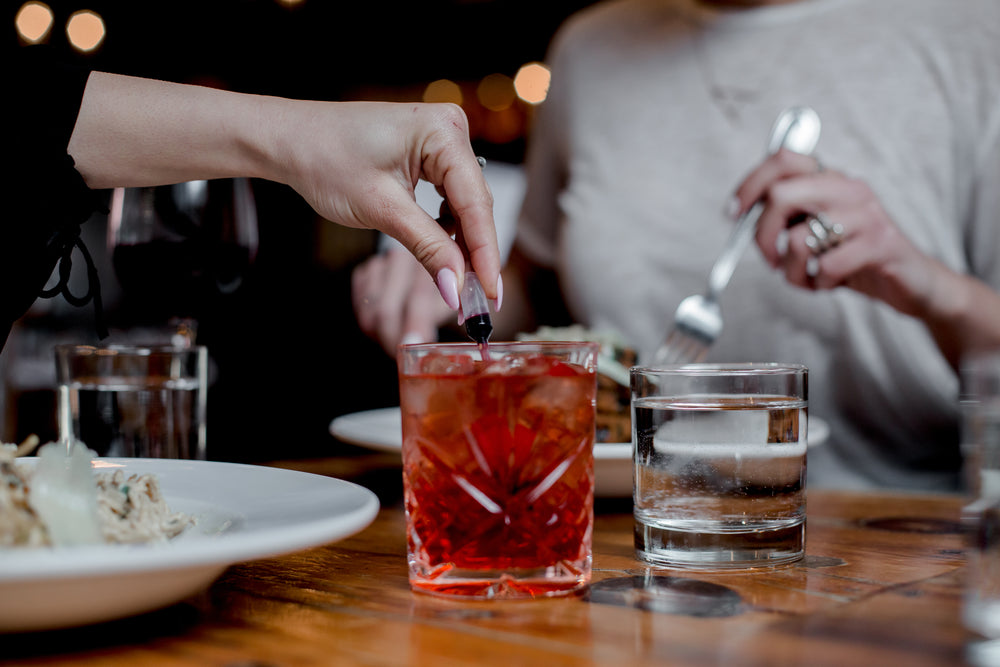 a hand adds red coloring to a crystal glass