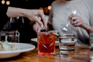 a hand adds red coloring to a crystal glass