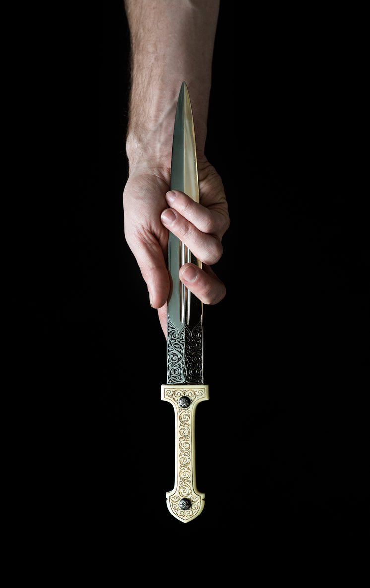 A Hand Clasps An Ornate Dagger By The Blade