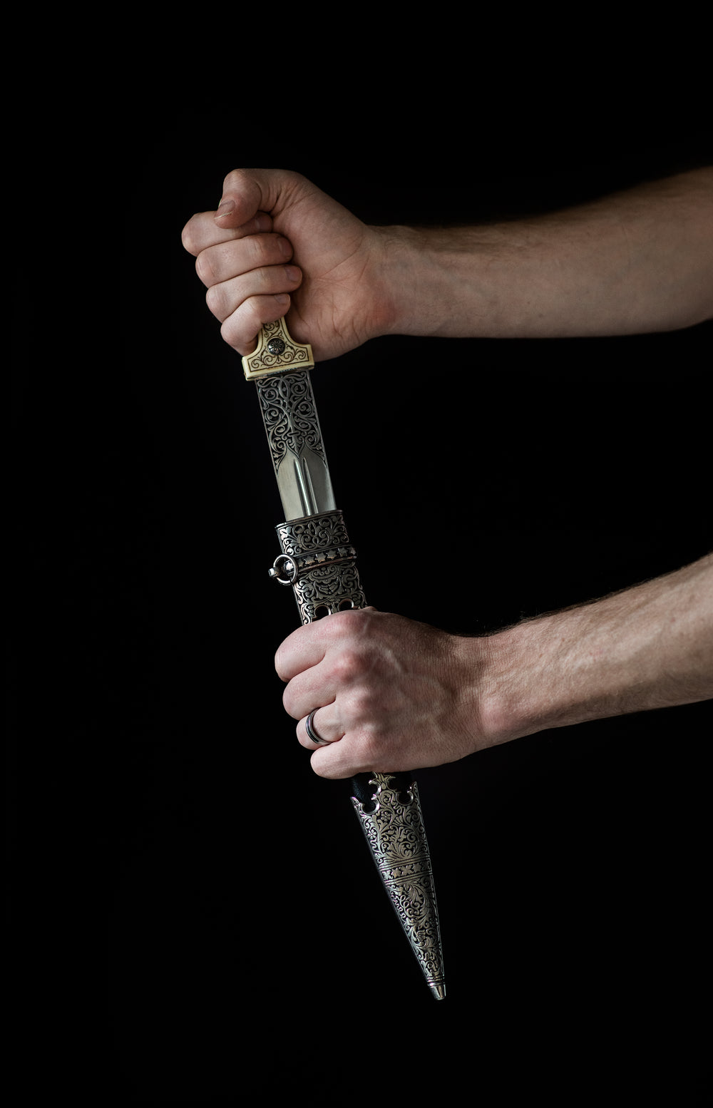 a hand draws an ornate dagger from its sheath