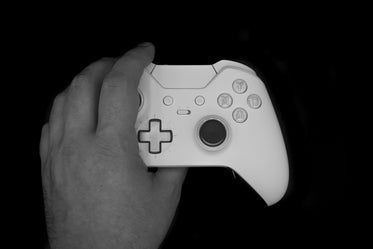 a hand grabbing a gaming controller against a black background