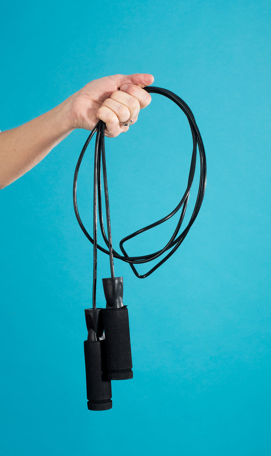 a hand grips a black gathered jump rope