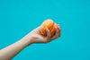 a hand holds a ripe peach