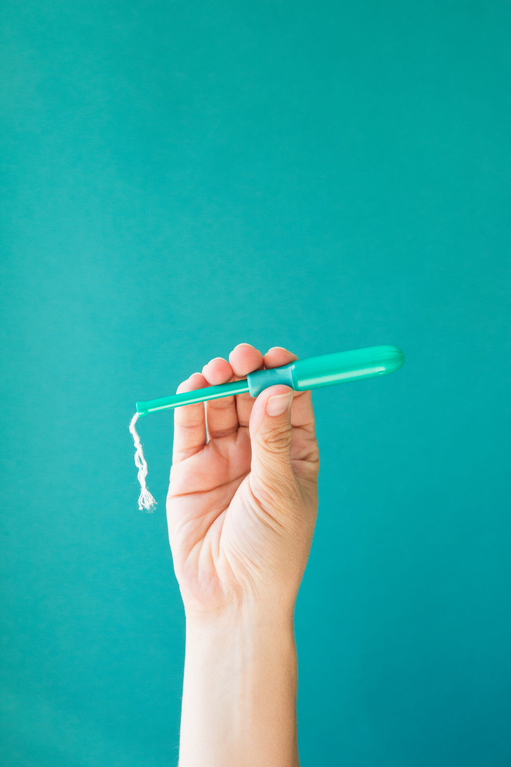 a hand holds a tampon applicator