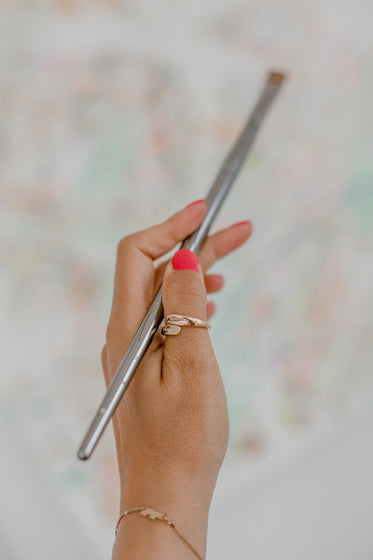 a hand holds silver paint brush
