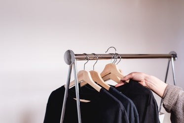 a hand removes a sweater from a clothing rack