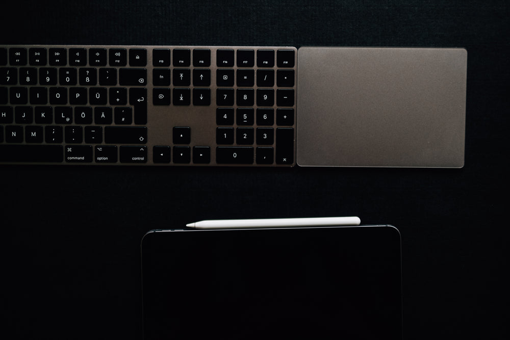 a keyboard and tablet on a black surface