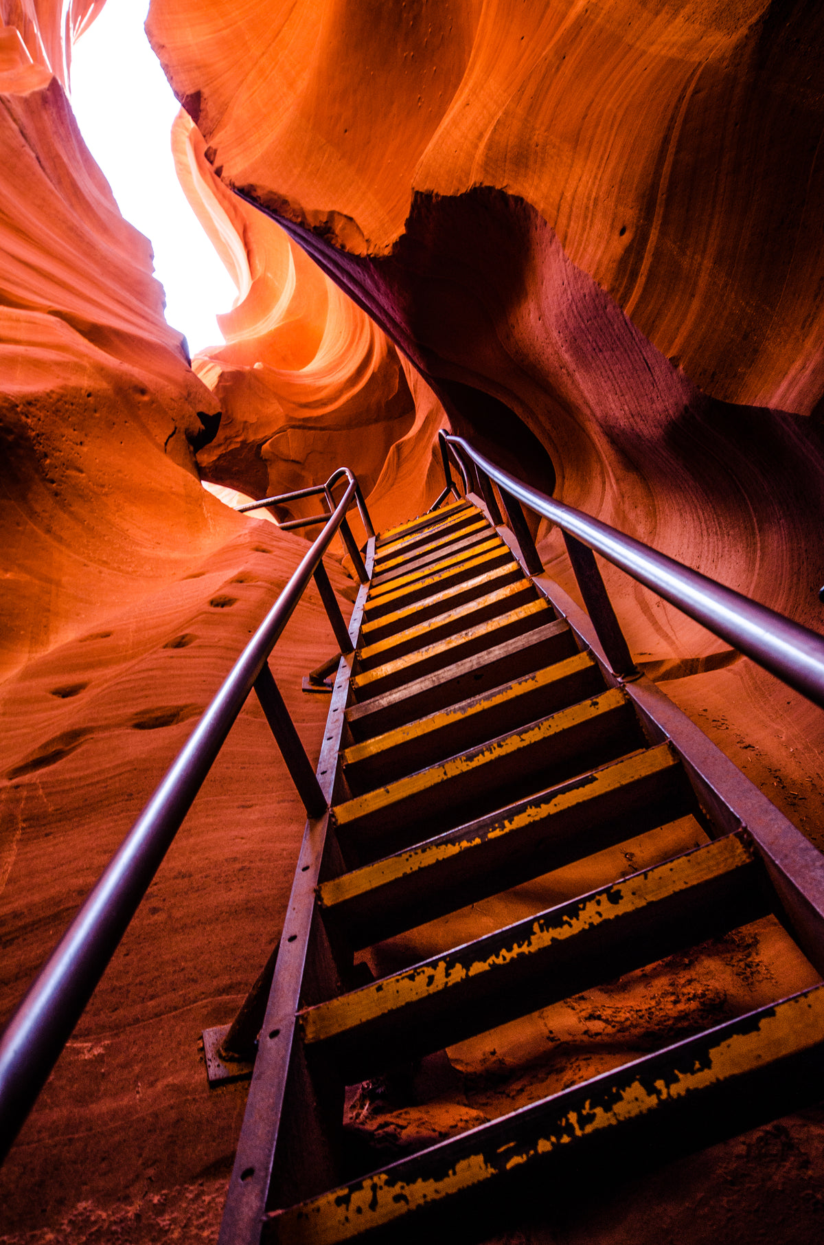 a ladder scales the steep sides of a red sandstone cave