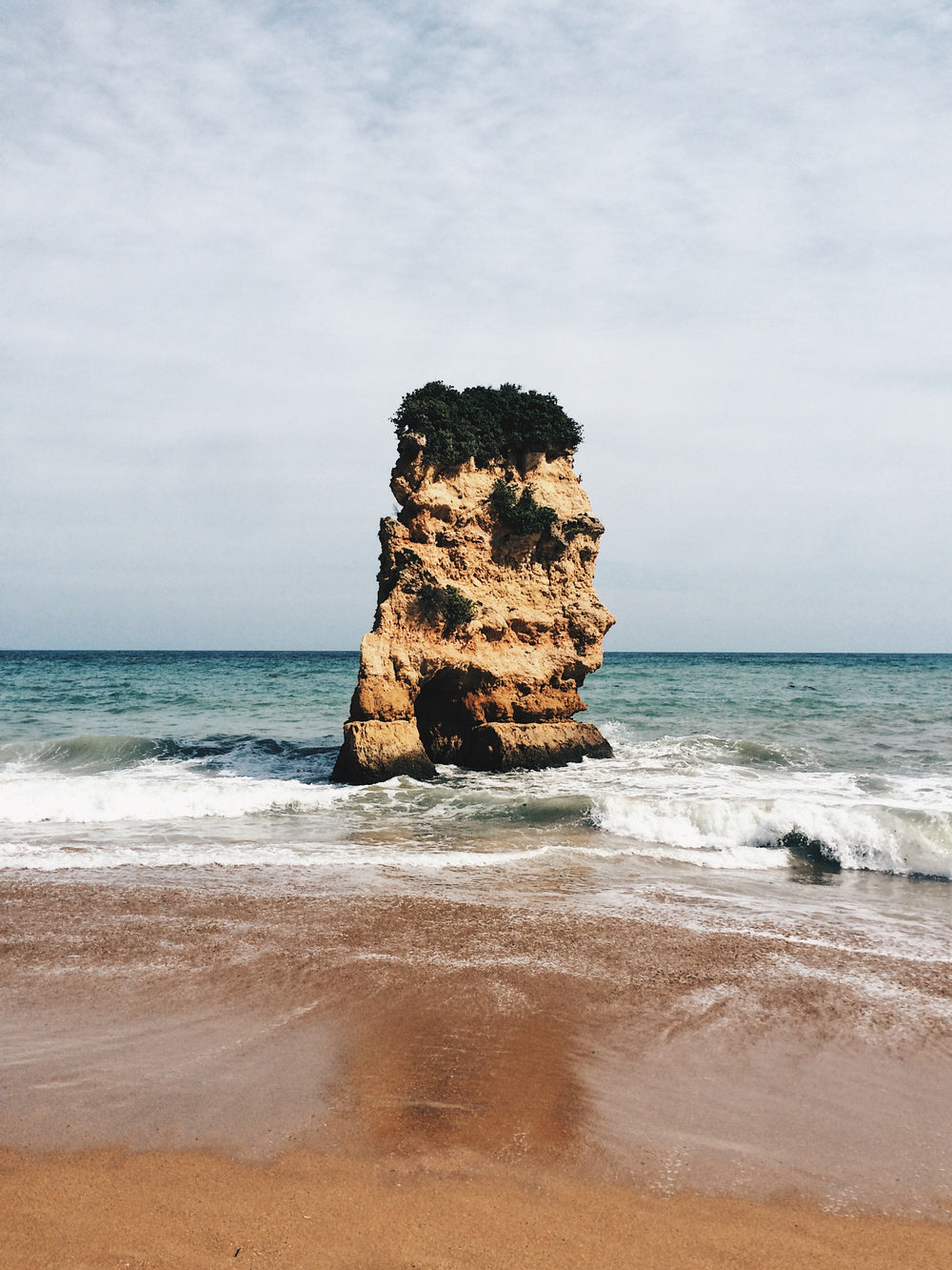 a large rock stands guard in the middle of the ocean