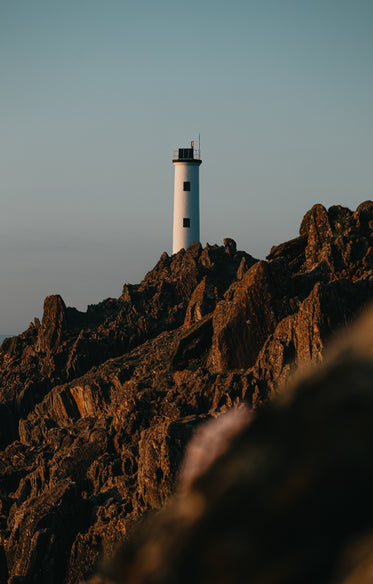 a lighthouse sits on top of a sharp mountain ridge