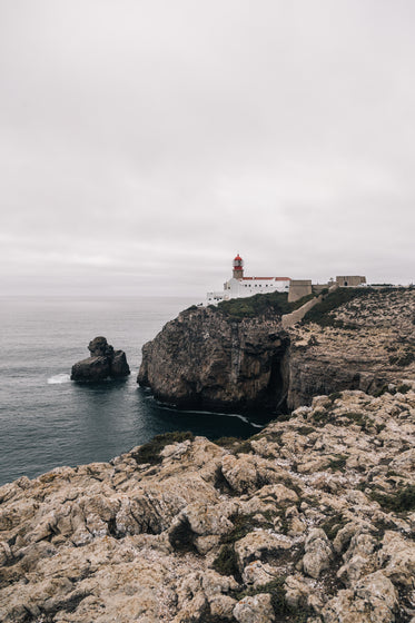 a lighthouse watches over a rocky coastline