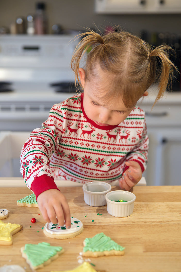 A Little Girl Concentrates As She Decorates Cookies