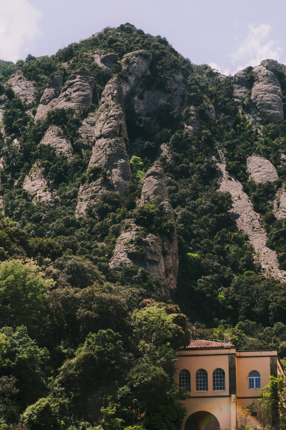 a little villa at the base of a green rocky hill