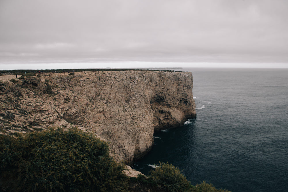 a long rock plateau reaches out into the cold grey sea