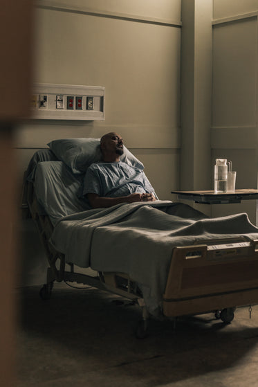 a male hospital patient rests head on pillows in bed