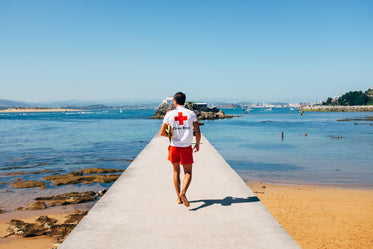 a male lifeguard patrols a concrete pier on a beach