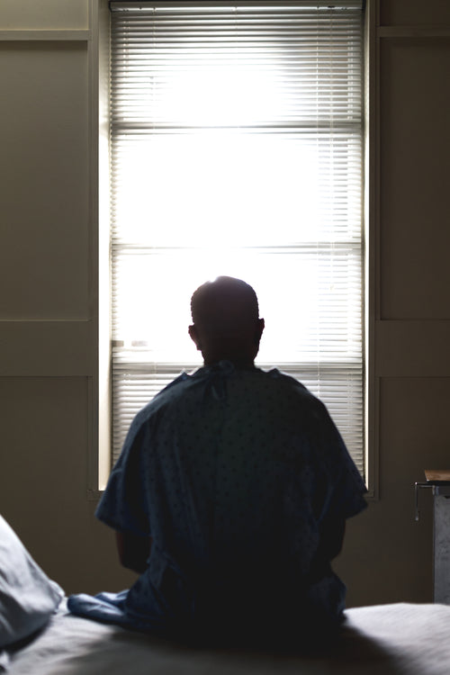 a male patient on a hospital bed silhouetted by window light