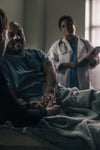 a male patient smiles while holding the hand of a friend