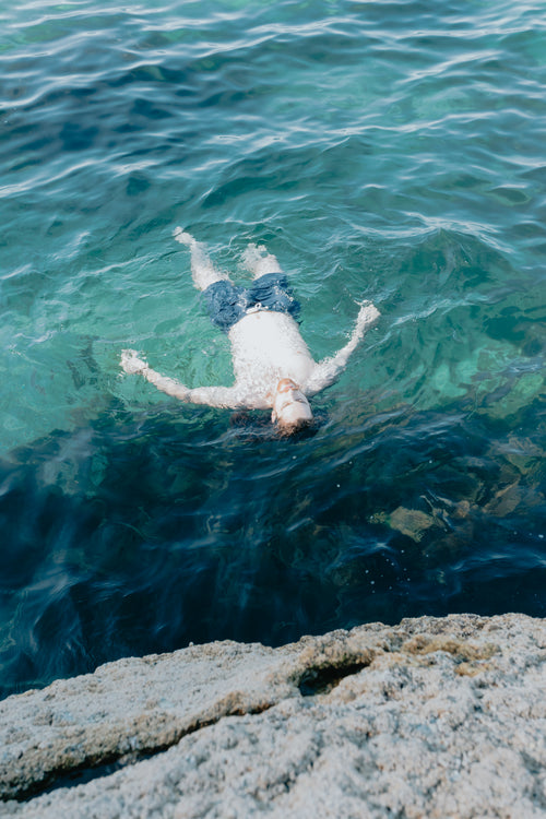 a man floats on his back in clear blue water