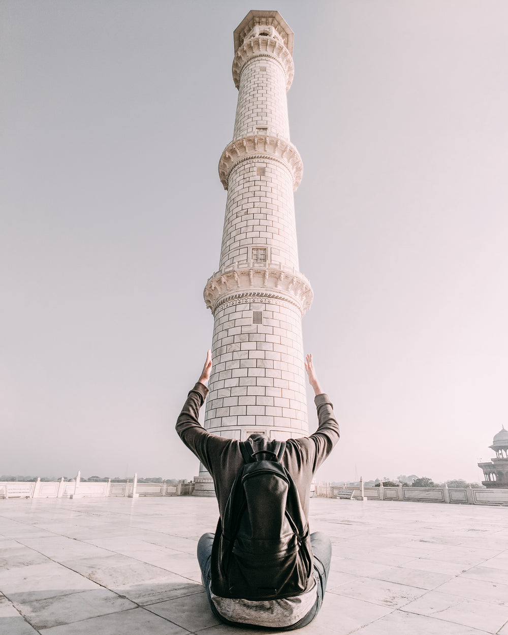 a man frames the base of a tower with his arms