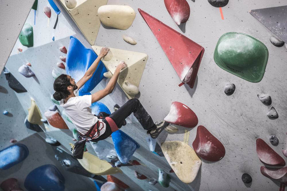 a man hangs from the side of a rock climbing wall