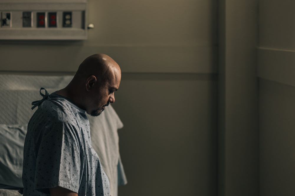 a man in a hospital room stares down at the floor