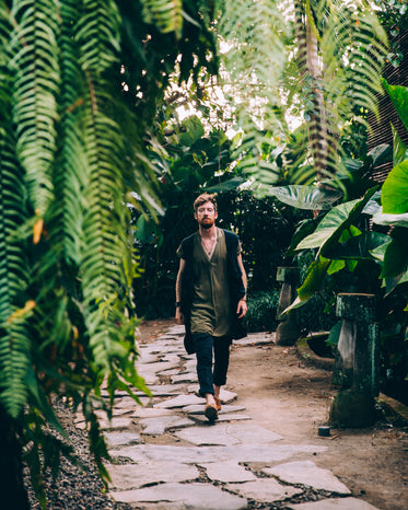 a man in sandals treads a path through ferns