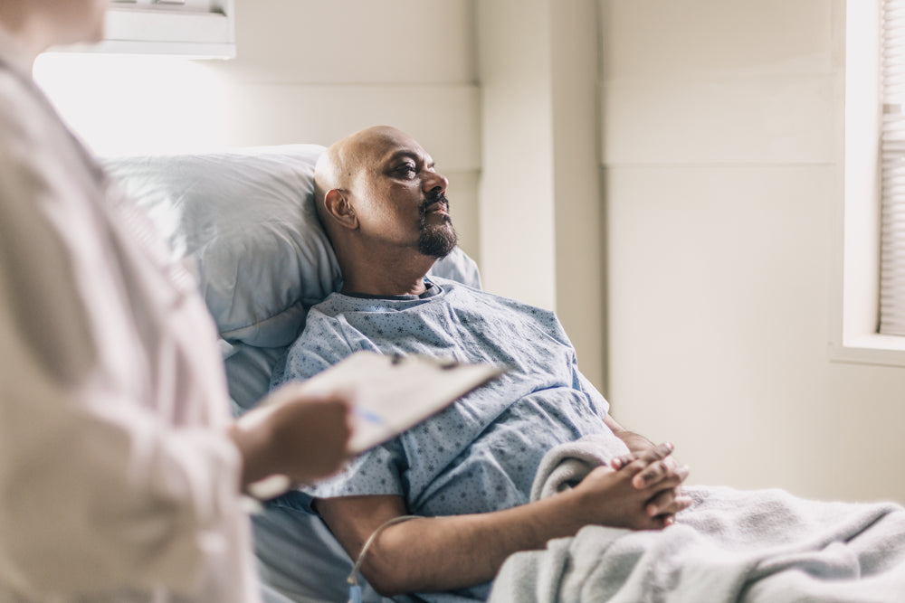 a man lies in a hospital bed as a doctor reads his chart