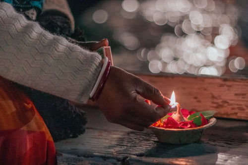 a man lights the wick of a aarti