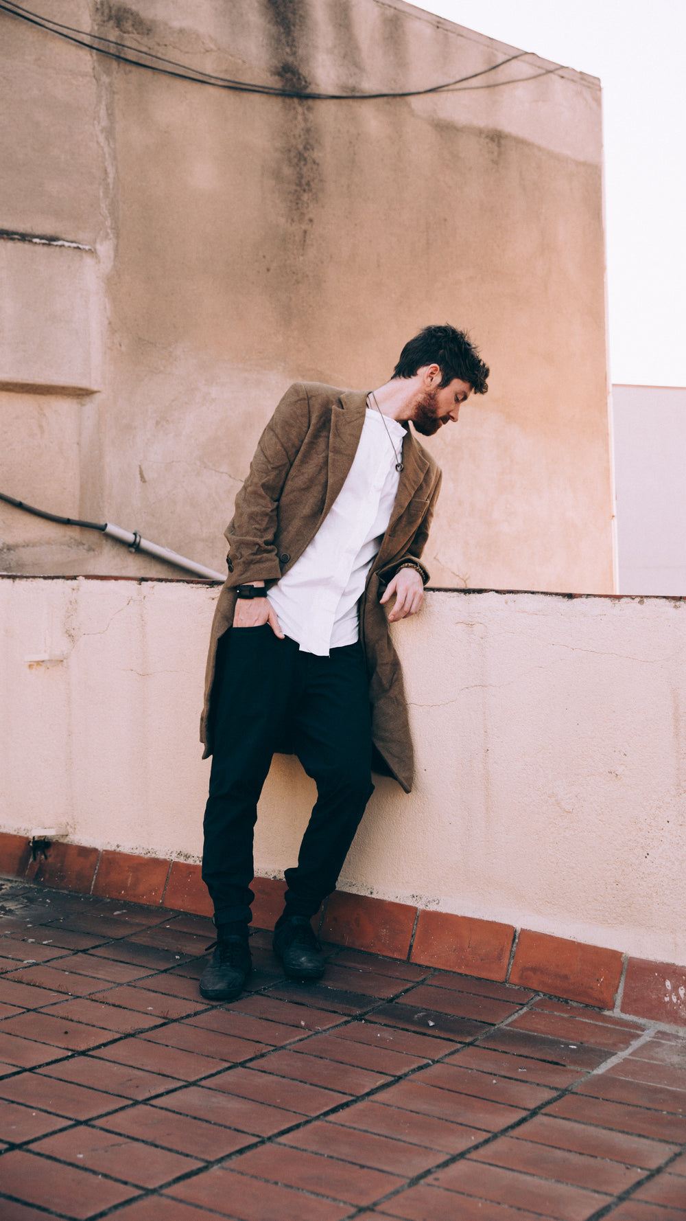 a man looks to the street below from a rooftop