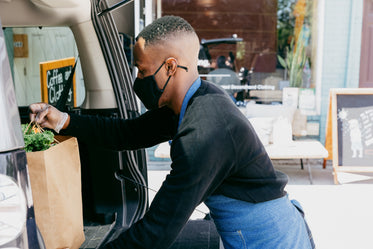 a man places customer order in back of car