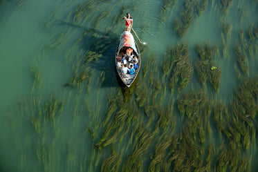 a man pushing a small boat across shallow waters