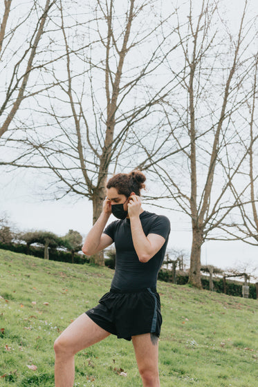 a man putting on his black face mask outdoors