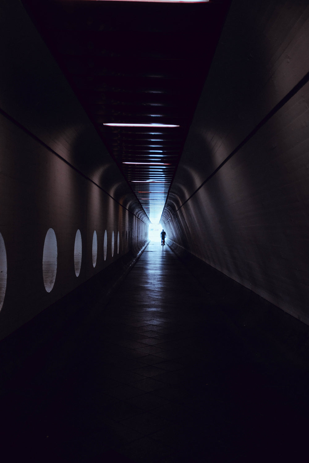 a man rides a bicycle through a tunnel