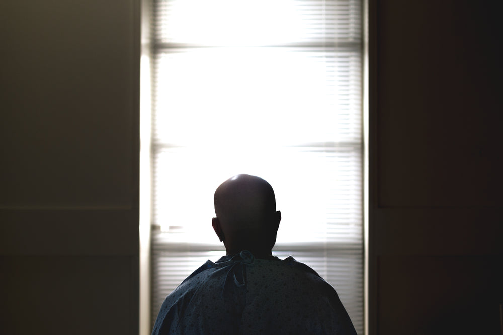 a man sat on a hospital bed silhouetted against the window