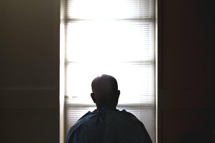 A Man Sat On A Hospital Bed Silhouetted Against The Window