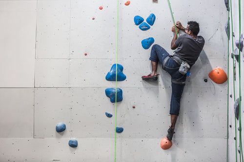 a man scales the side of a rock climbing wall