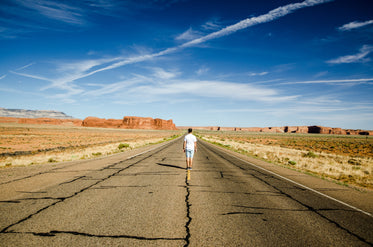 a man stands on the road markings of a desert highway