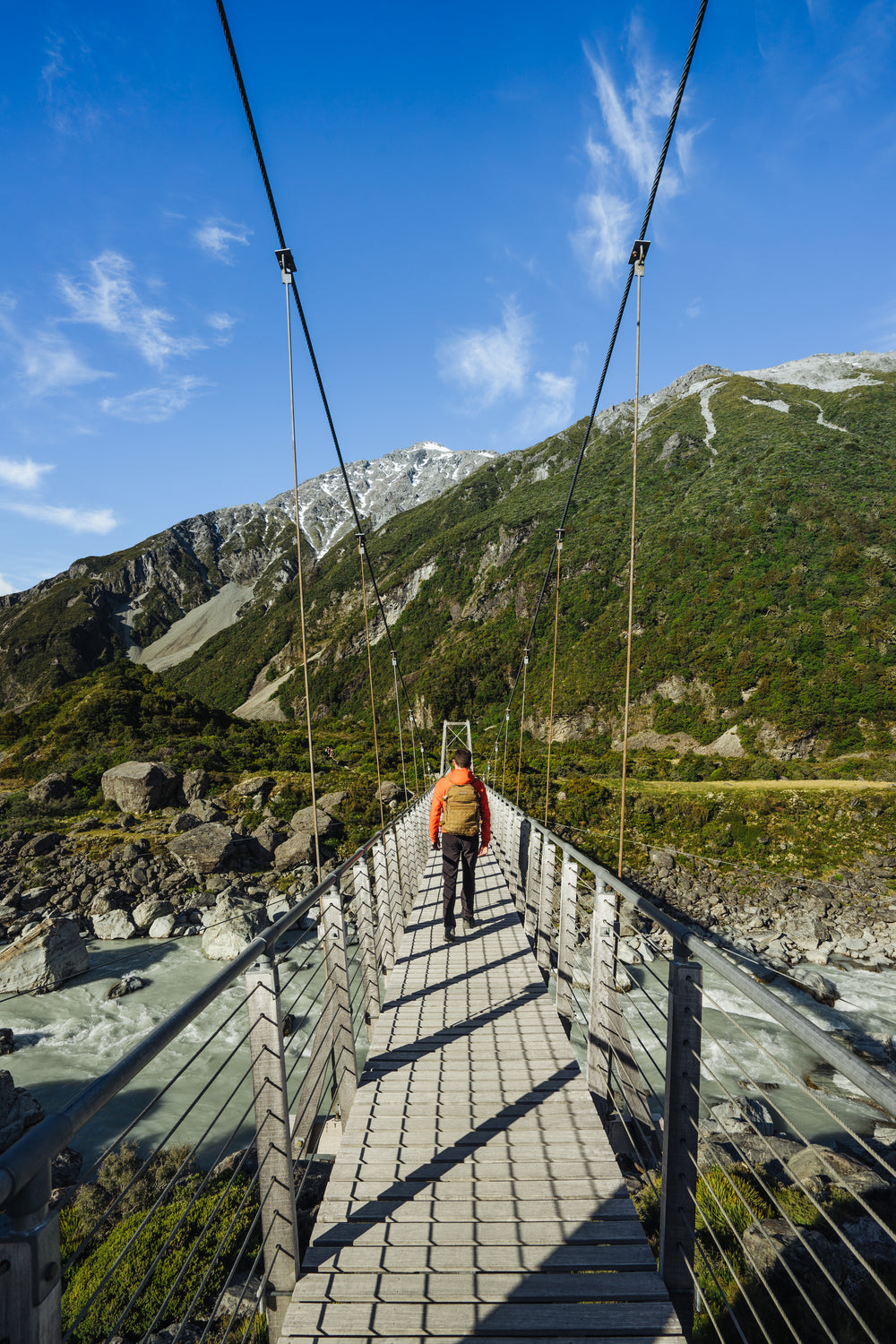a man walking across a suspension bridge