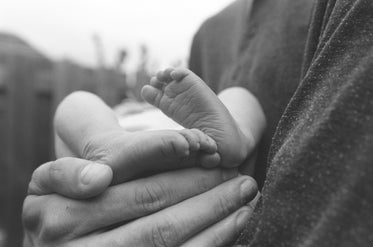 a mans large hand cradles a newborn baby