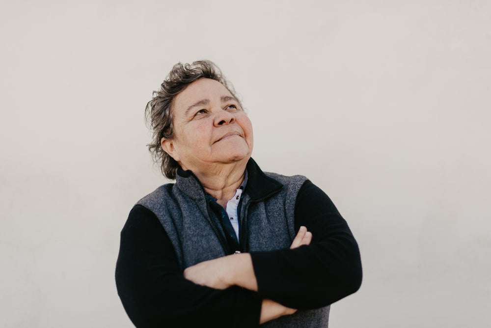 a mature woman ponders the sky with arms crossed