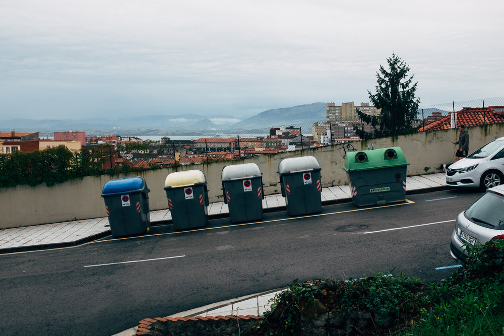 a mix of public recycling bins at the side of a steep road