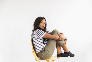 a model holds knee to chest on chair pensively